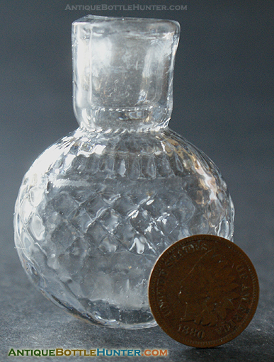 A colorless round flattened blown-three-mold smelling bottle. --- AntiqueBottleHunter.com
