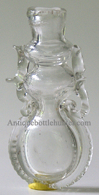 An early colorless smelling bottle or scent adorned with ribbons, rigaree and pontil mark. Height, 2 - 3/8 in. Width, 1 - 1/8 in. --- AntiqueBottleHunter.com