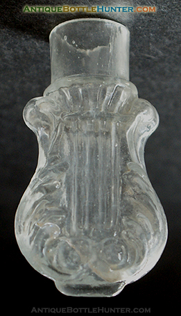 A colorless scroll or lyre type mold blown smelling bottle. --- AntiqueBottleHunter.com